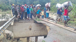 Locals cross the over flooded Bena Bridge. Credit: The National
