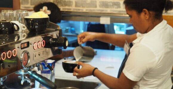 A barista pouring milk into a coffee at the Duffy cafe.